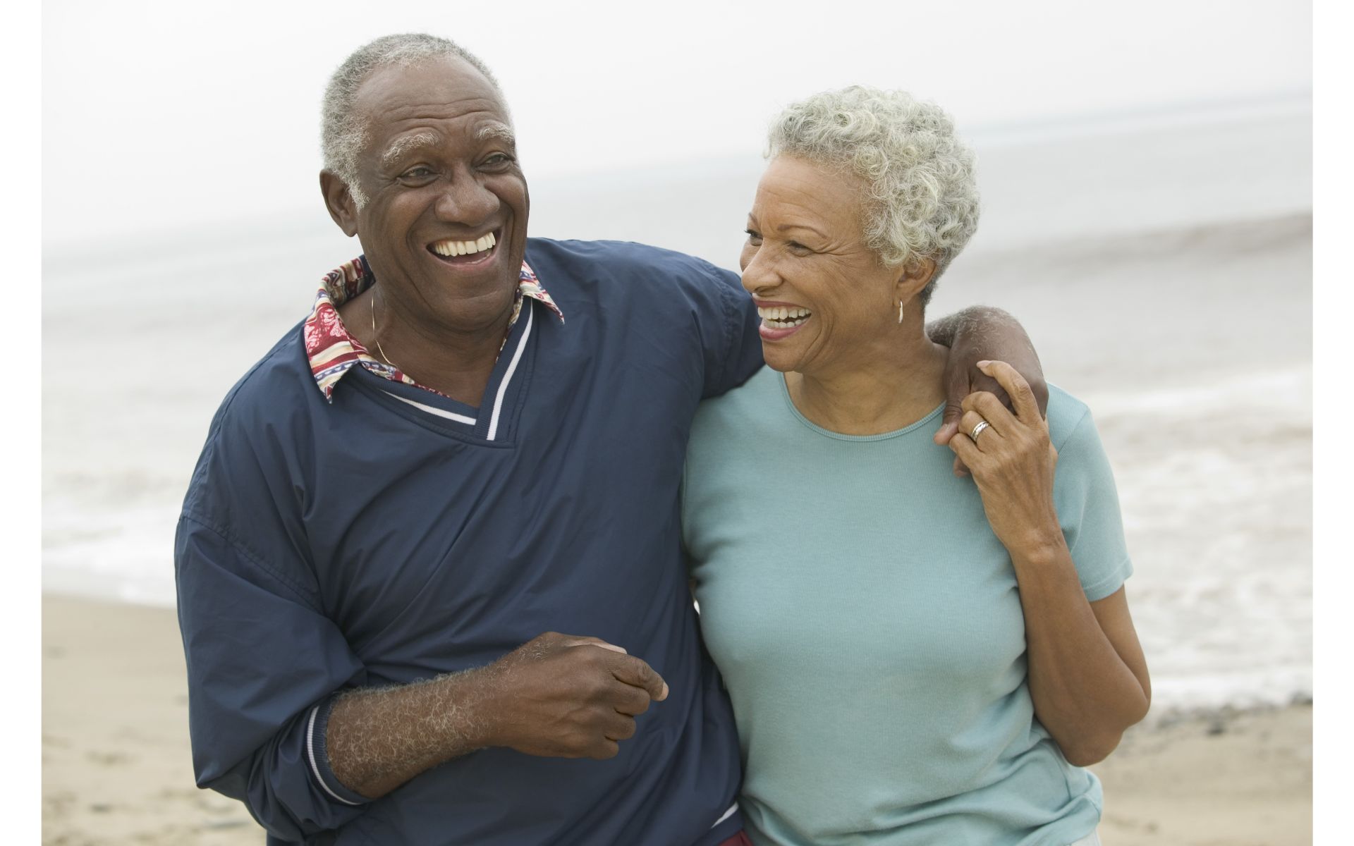 Older couple smiling and holding each other outside.