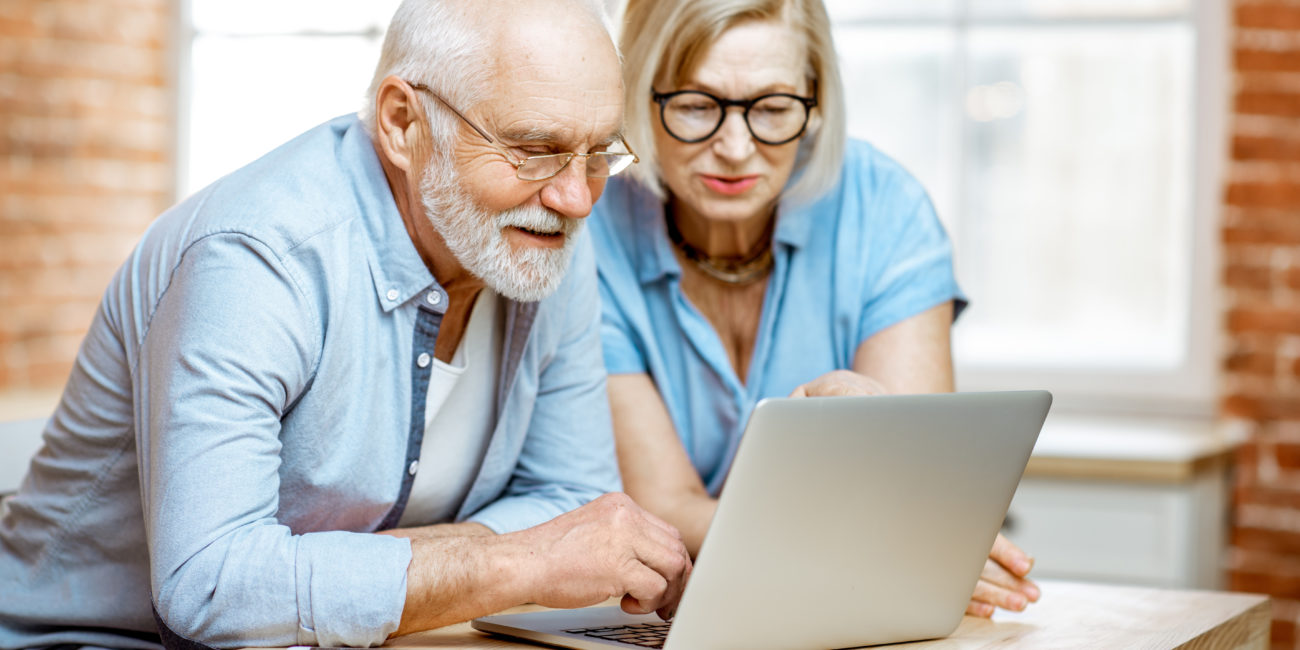 Older couple looking at computer screen. Article about electronic caregiving through technology.