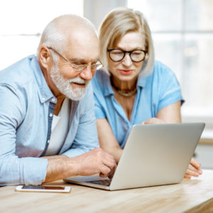 Older couple looking at computer screen. Article about electronic caregiving through technology.