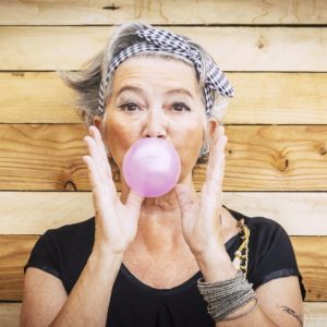 Woman in bandana blowing bubble gum. Cover image for article about aging in place.