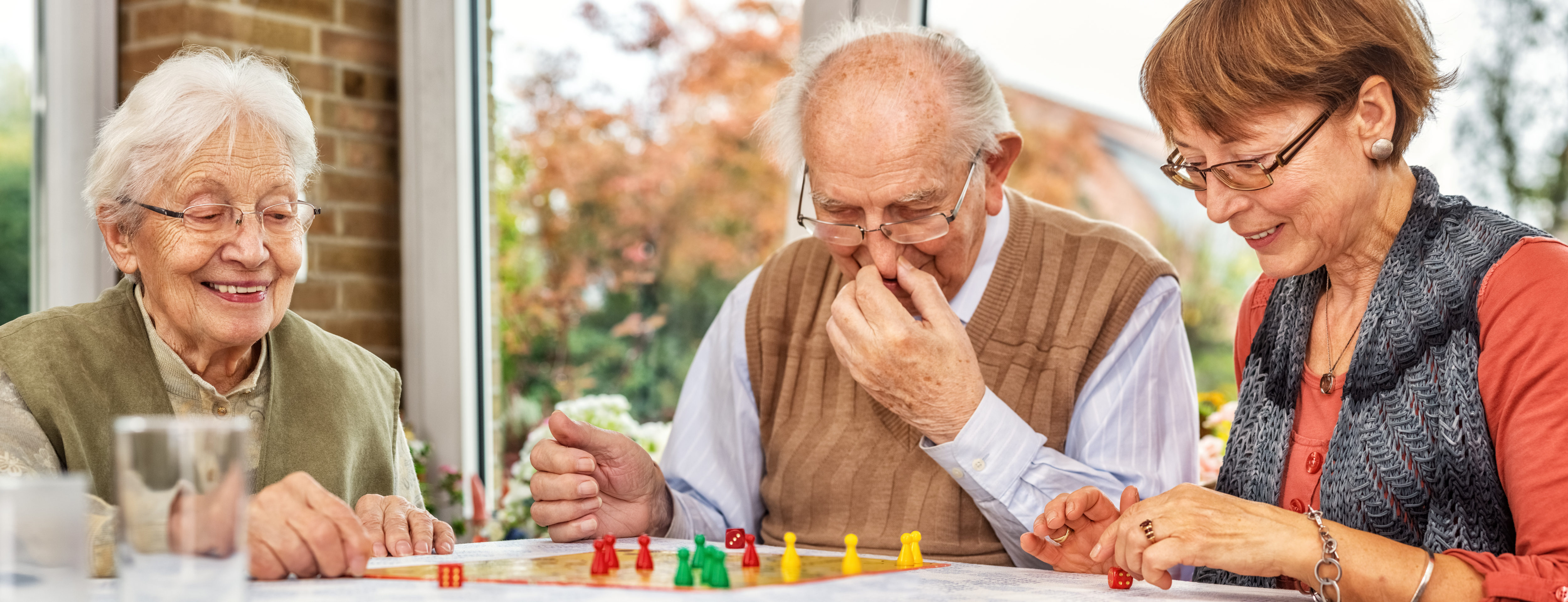 Older man playing board game. Cover image for article about games to play with older adults.