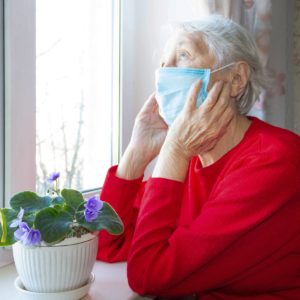 An older woman wearing a mask. Cover image for an article on keeping homes disease-free.