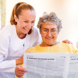 Older woman looking at newspaper with friend.