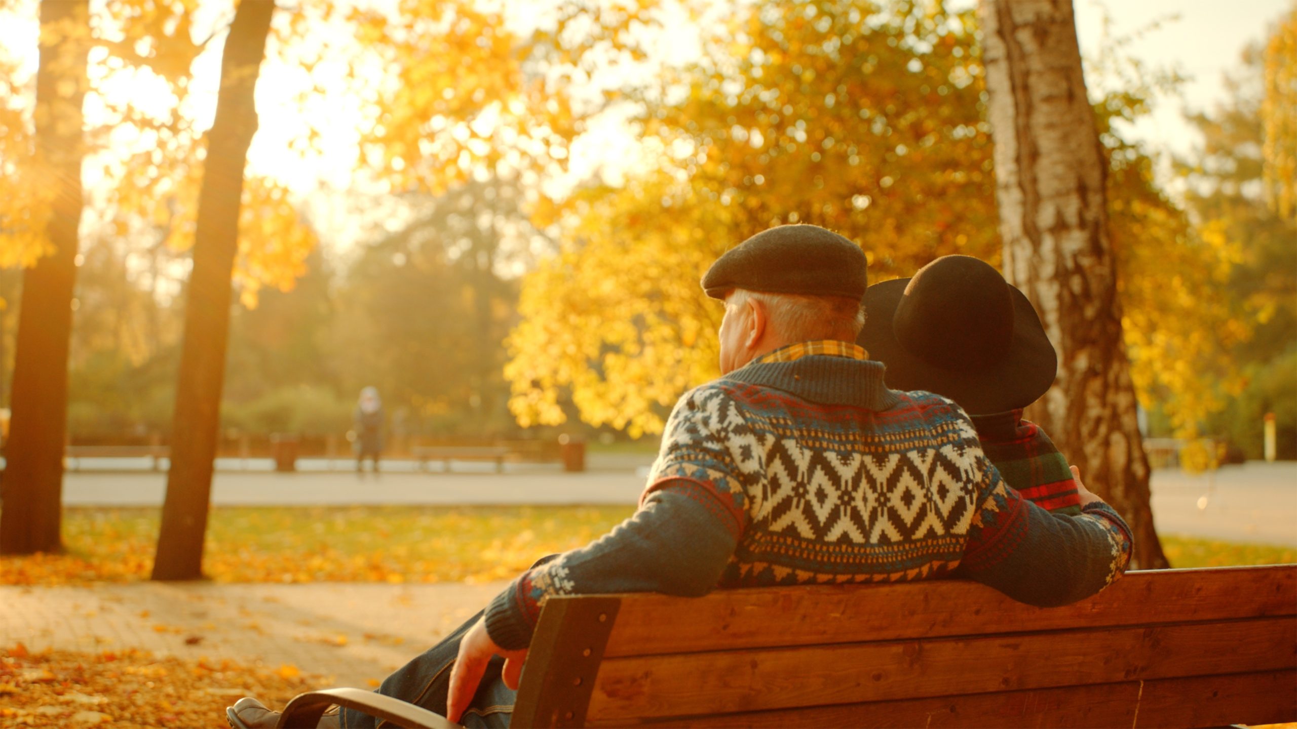 Senior couple sitting on bench at sunset. Cover image for article on Sundowning.