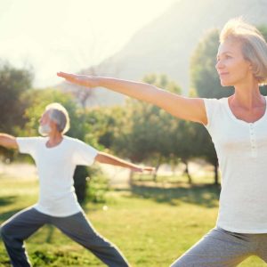 Senior family doing yoga exercises outside. Cover image for article about exercises for seniors.