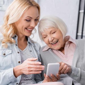 Older adult and family member looking at cell phone together. Cover image for article about technology for older adults.