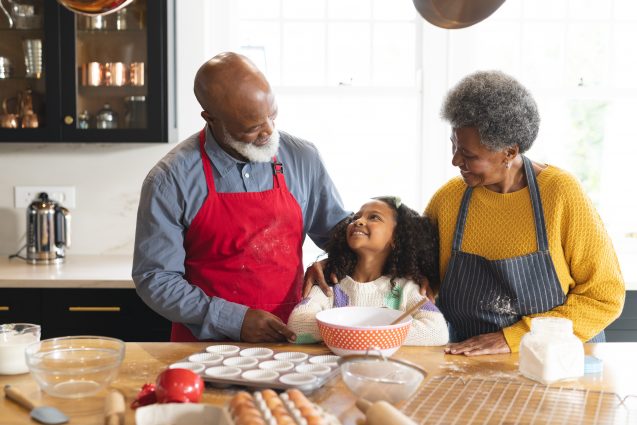 Image of happy african american grandparents and granddaughter baking in kitchen